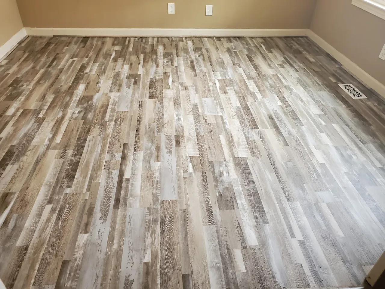 Weathered gray luxury vinyl plank flooring installed in a bedroom