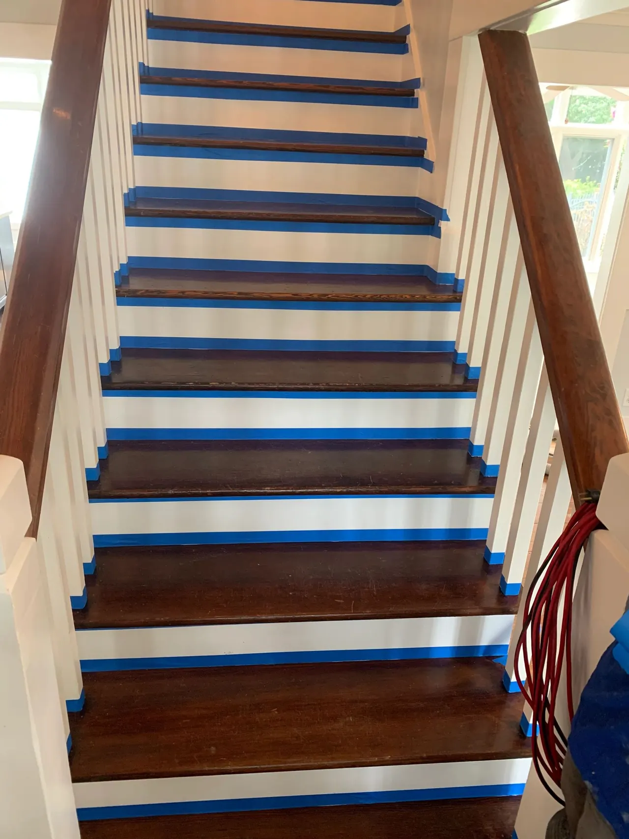 Stair tread refinishing in progress with taped white risers